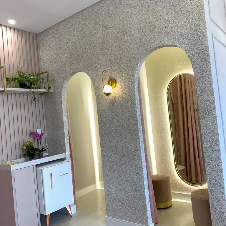Provador com arcos iluminados, espelho de moldura dourada e bancada planejada