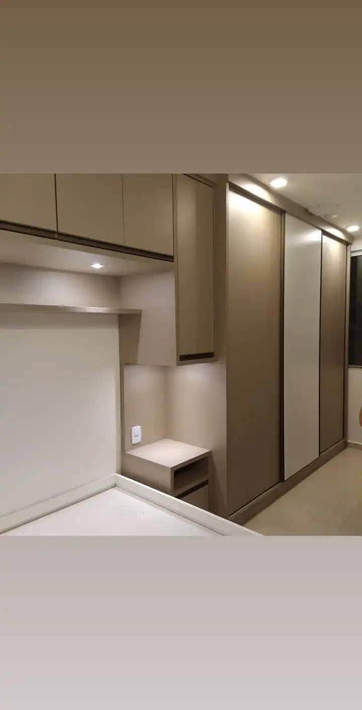 Quarto planejado com guarda-roupa de portas de correr e armários sobre a cama