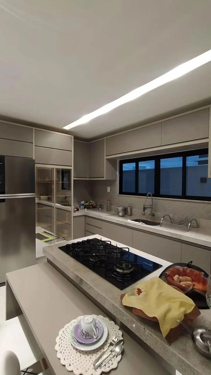 Cozinha planejada com bancada em pedra, cooktop na ilha e armários superiores